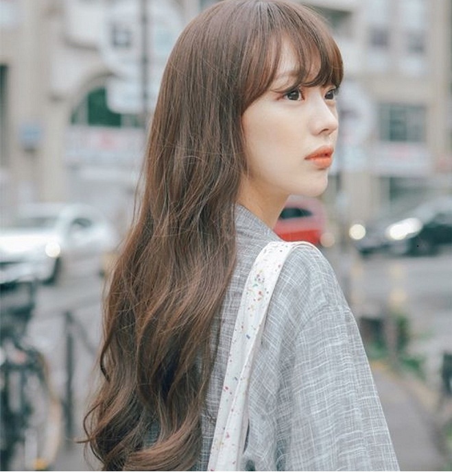 cô gái mặc áo khoác xám mái tóc dài ngang lưng uốn nhẹ đuôi